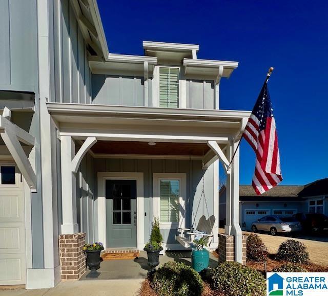 view of exterior entry with board and batten siding, a porch, and a garage