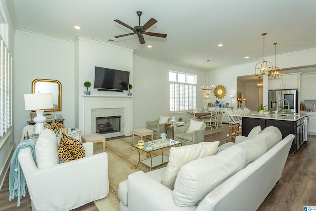 living room with dark wood-style floors, a fireplace, crown molding, and recessed lighting