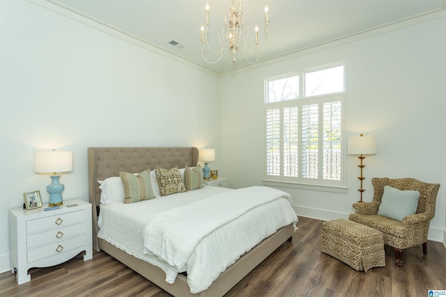 bedroom featuring an inviting chandelier, wood finished floors, visible vents, and crown molding