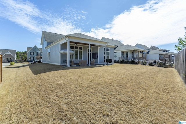 view of front facade with a residential view, fence, a ceiling fan, and a front yard