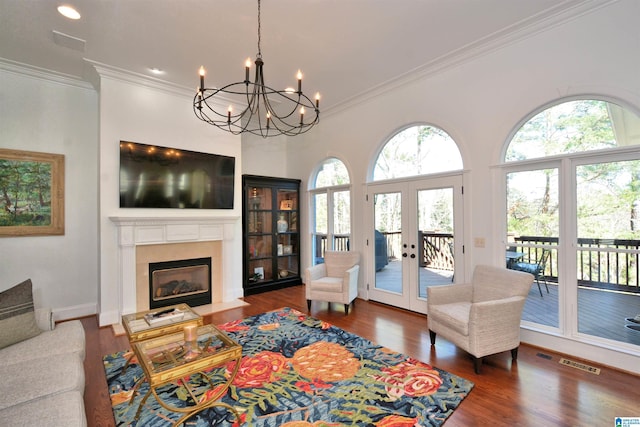 living area with visible vents, a fireplace with flush hearth, wood finished floors, french doors, and a wealth of natural light