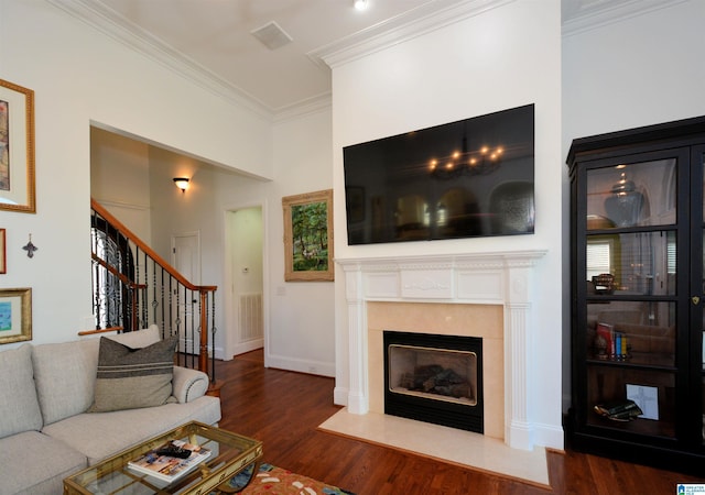 living room with wood finished floors, a fireplace with flush hearth, visible vents, stairway, and crown molding