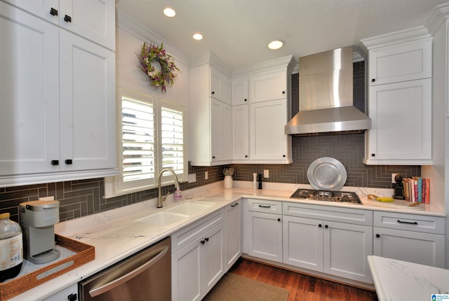 kitchen with stainless steel appliances, white cabinets, a sink, and wall chimney range hood