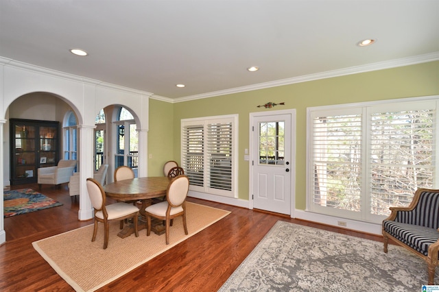 dining area featuring plenty of natural light, crown molding, arched walkways, and wood finished floors