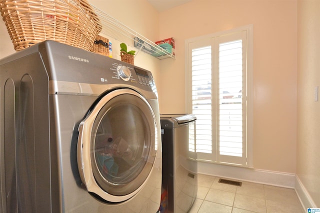 clothes washing area with visible vents, washing machine and dryer, a healthy amount of sunlight, tile patterned flooring, and laundry area