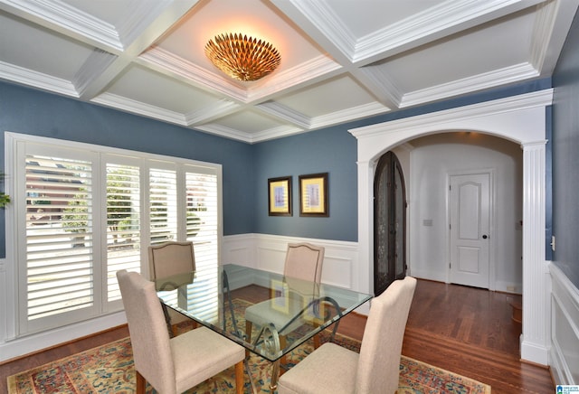 dining room featuring arched walkways, coffered ceiling, wood finished floors, and beam ceiling