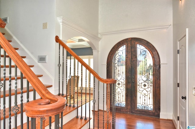 foyer featuring arched walkways, french doors, visible vents, a high ceiling, and wood finished floors