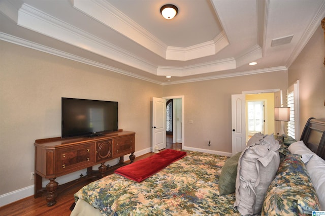 bedroom with baseboards, a raised ceiling, wood finished floors, and ornamental molding