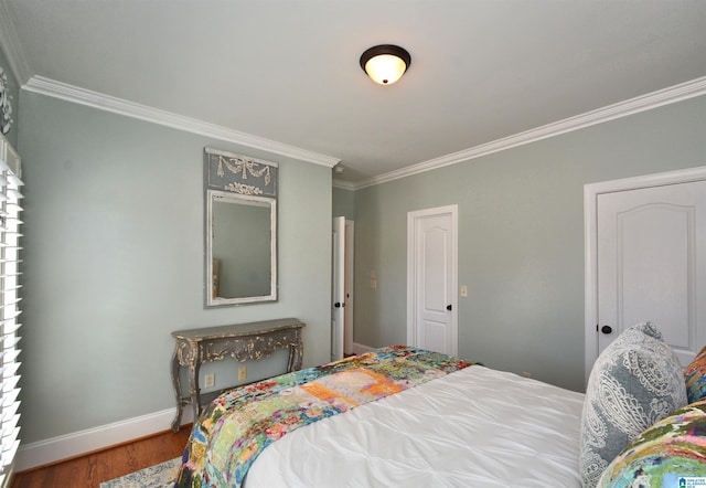 bedroom with ornamental molding, baseboards, and wood finished floors