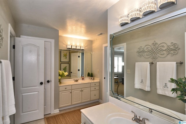 full bathroom with visible vents, two vanities, and a sink