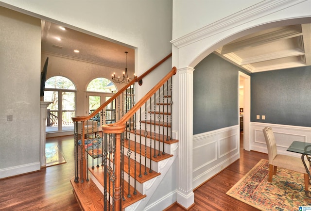 staircase with arched walkways, ornamental molding, a wainscoted wall, and wood finished floors