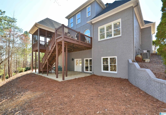 rear view of house featuring a wooden deck, stairs, a patio, and brick siding