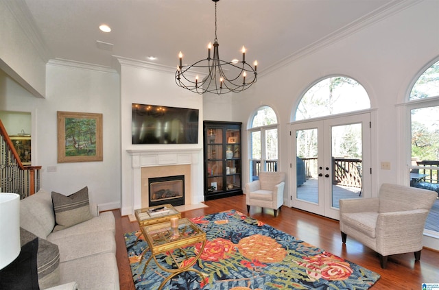 living room with a fireplace with flush hearth, wood finished floors, stairs, french doors, and ornamental molding