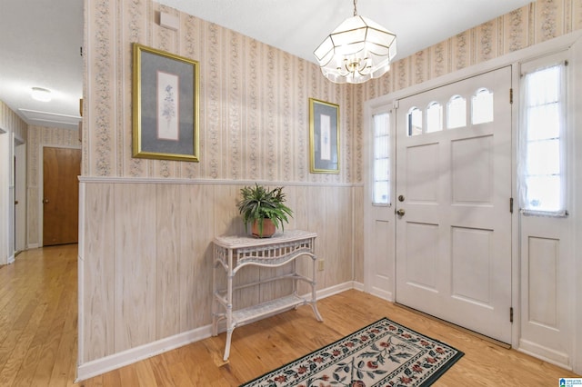 foyer featuring wainscoting, wood finished floors, and wallpapered walls