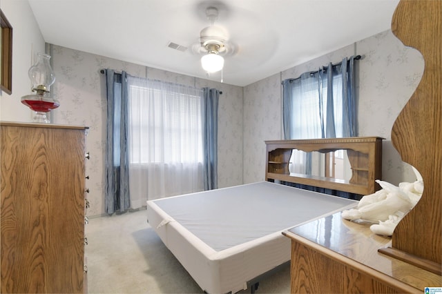 bedroom featuring light carpet, wallpapered walls, visible vents, and a ceiling fan