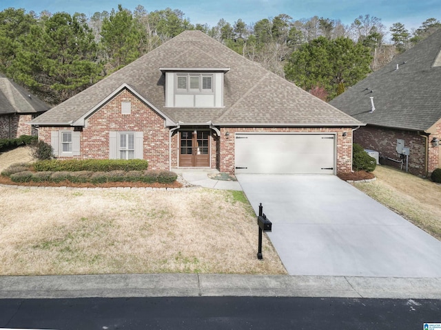 view of front of property with driveway, a shingled roof, an attached garage, and brick siding