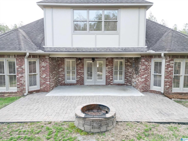 back of house featuring a fire pit, a patio, roof with shingles, french doors, and brick siding