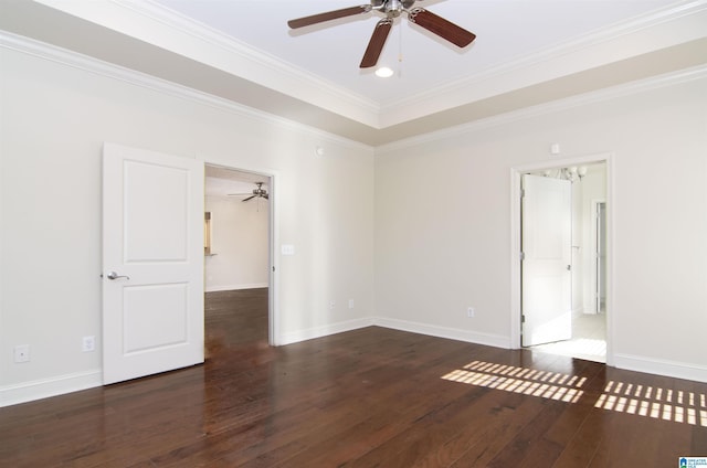 empty room featuring baseboards, dark wood-style floors, ceiling fan, a tray ceiling, and crown molding