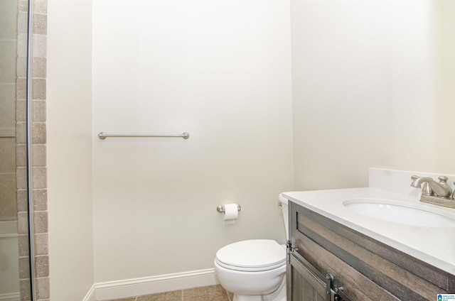 bathroom with toilet, tile patterned floors, baseboards, and vanity