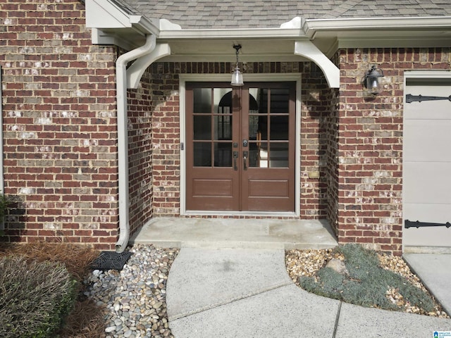 entrance to property featuring french doors, roof with shingles, and brick siding