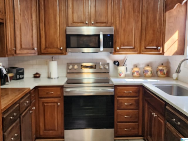 kitchen featuring a sink, brown cabinetry, stainless steel appliances, and light countertops