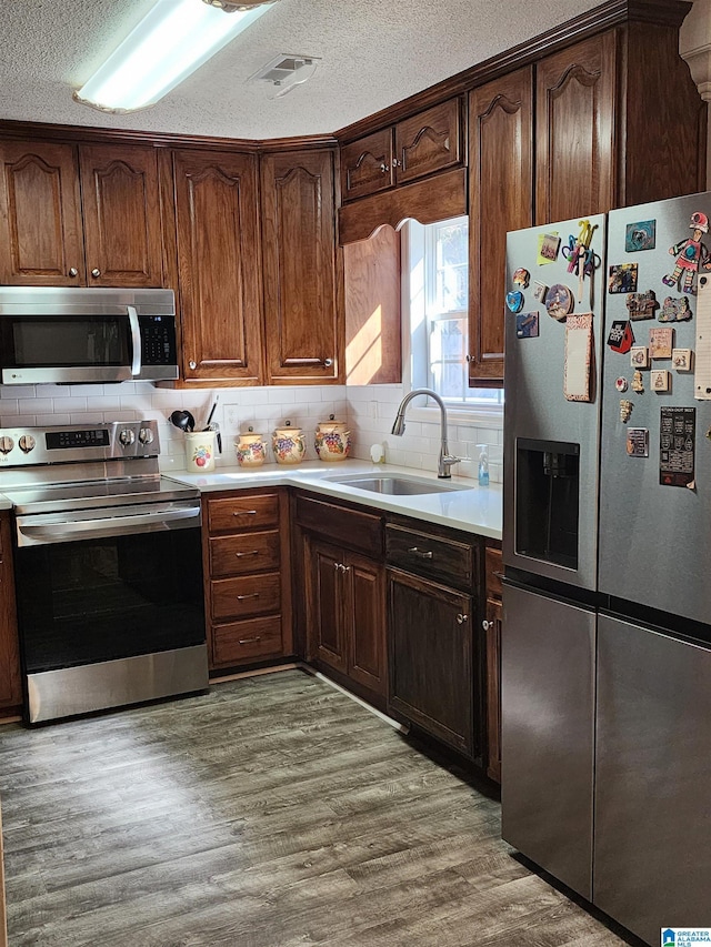 kitchen featuring stainless steel appliances, light wood-type flooring, a sink, and light countertops