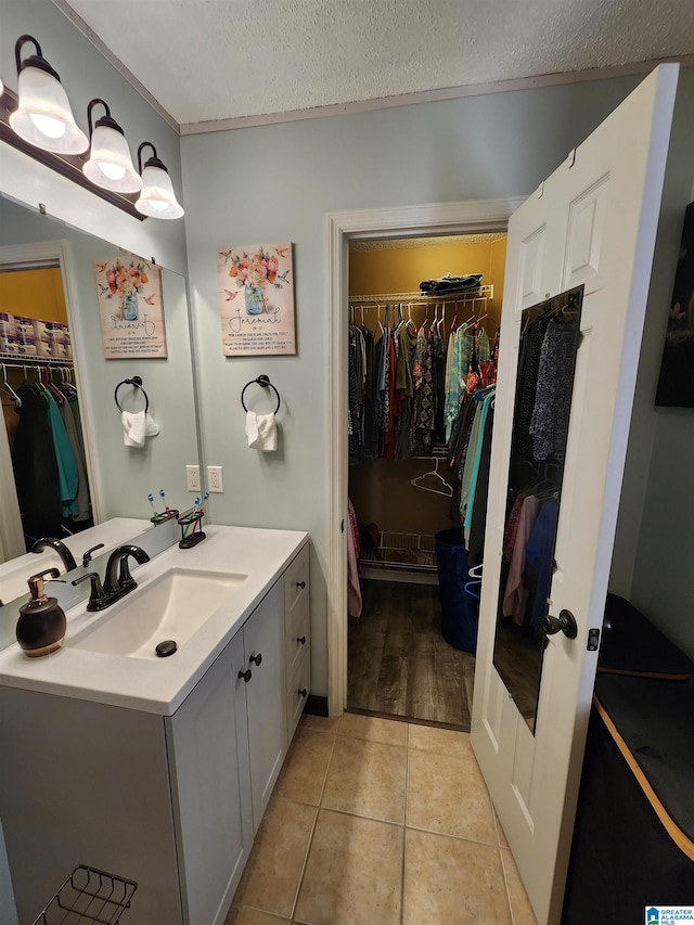 bathroom featuring tile patterned flooring, a spacious closet, a textured ceiling, and vanity