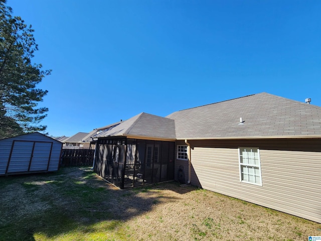 back of house with an outbuilding, fence, a sunroom, a lawn, and a storage unit