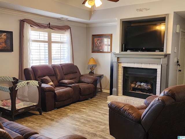 living area with ceiling fan, light wood finished floors, a fireplace, and crown molding