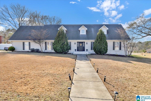 cape cod home with brick siding and a front yard