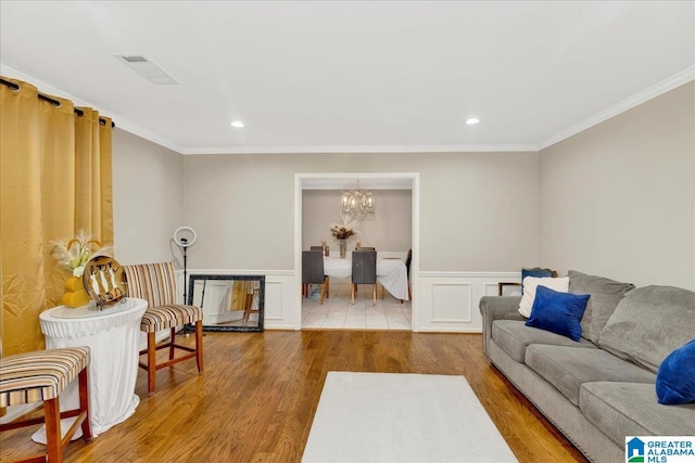 living area featuring crown molding, visible vents, wood finished floors, and wainscoting