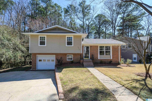 tri-level home featuring a garage, driveway, brick siding, and a front yard