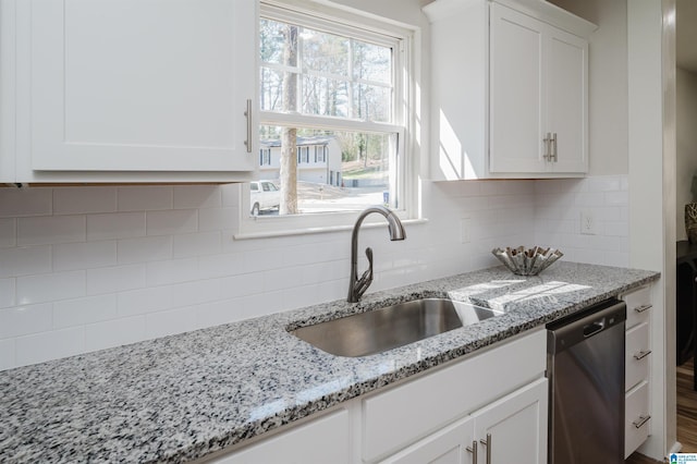 kitchen featuring light stone counters, a sink, white cabinets, dishwasher, and tasteful backsplash