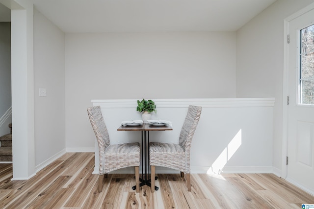 dining area with light wood-style flooring, stairway, and baseboards