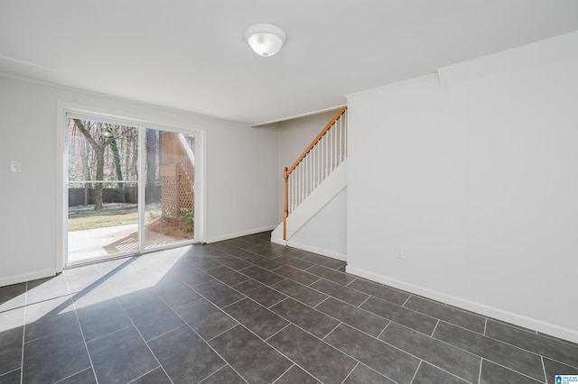 empty room with stairs, baseboards, crown molding, and dark tile patterned flooring