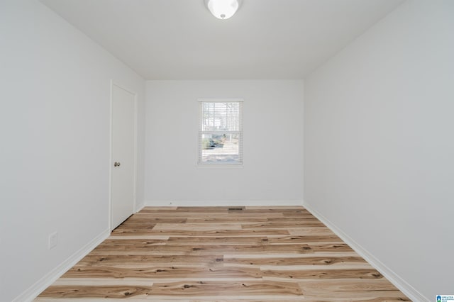 empty room featuring light wood finished floors and baseboards