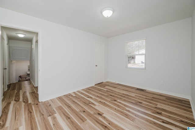 spare room with light wood-style flooring, visible vents, and baseboards