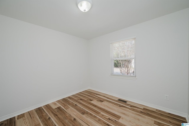 spare room featuring baseboards, visible vents, and wood finished floors