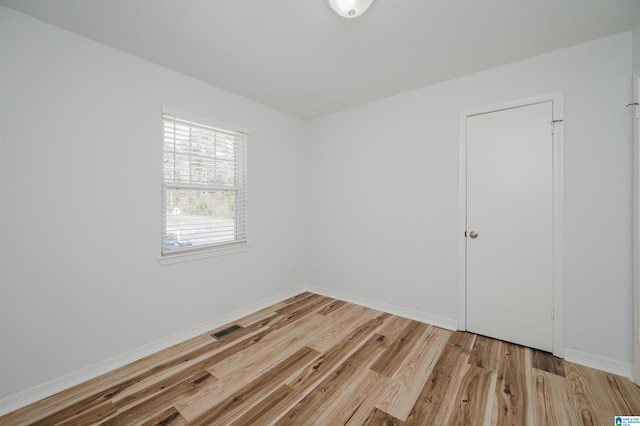 empty room featuring light wood-style floors, baseboards, and visible vents