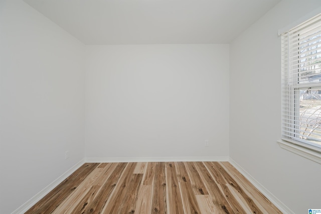 spare room with baseboards and wood finished floors