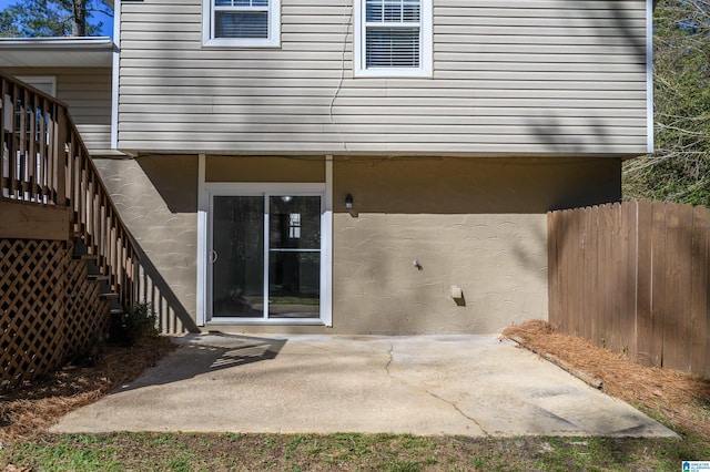 doorway to property with a patio area, fence, and stucco siding