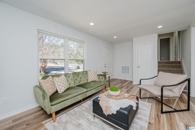 living room featuring stairway, visible vents, and light wood-style floors