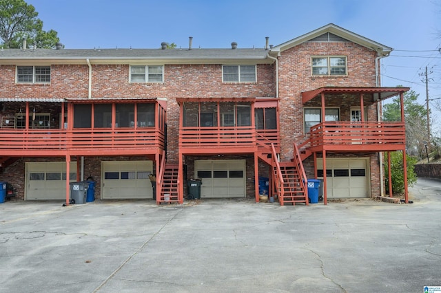 back of house featuring a garage, brick siding, and stairs