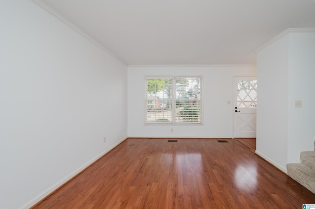 unfurnished room with ornamental molding, plenty of natural light, wood finished floors, and baseboards