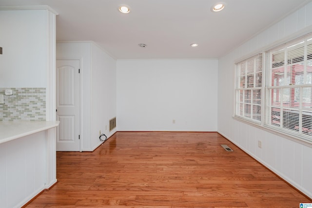 spare room with light wood-type flooring, visible vents, crown molding, and recessed lighting