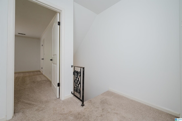 corridor featuring baseboards, an upstairs landing, visible vents, and light colored carpet