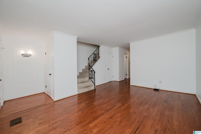 unfurnished living room featuring visible vents, ornamental molding, wood finished floors, baseboards, and stairs