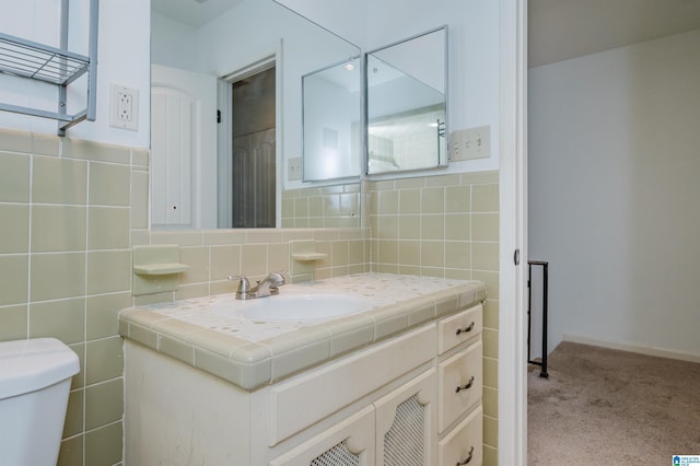 bathroom featuring toilet, tile walls, and vanity