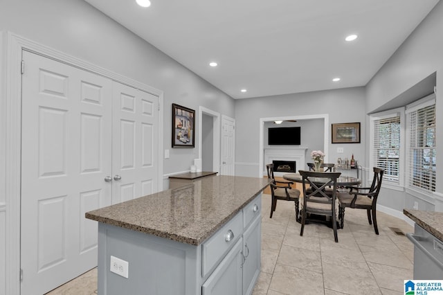 kitchen with stone countertops, recessed lighting, a fireplace, a center island, and dishwasher