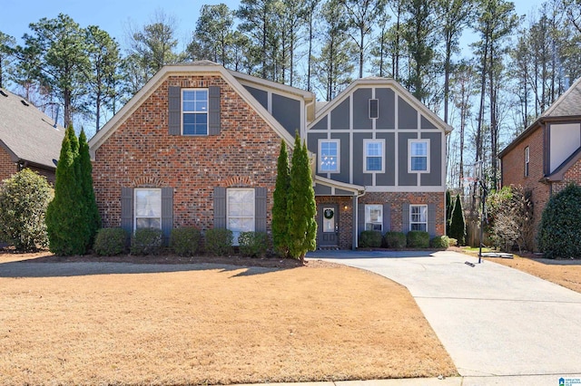 tudor home featuring concrete driveway and brick siding